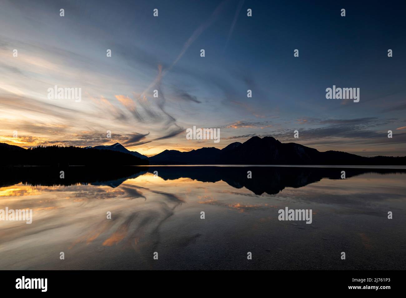 Simetsberg unfolds angel wings reflected in the water of Walchensee at sunset. Cloud formation in the shape of a wing. Stock Photo