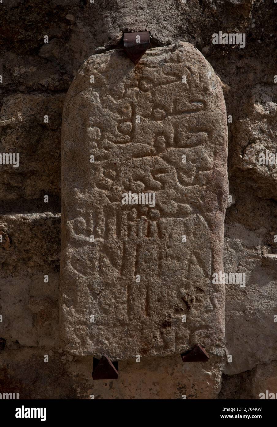 Stein mit arabischen und lateinischen Schriftzeichen an einer Wand im Burghof Stock Photo