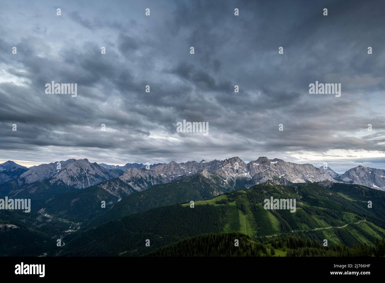 The Rhonberg and the ascending forest road, in the background the Karwendel in dense cloud cover. Stock Photo