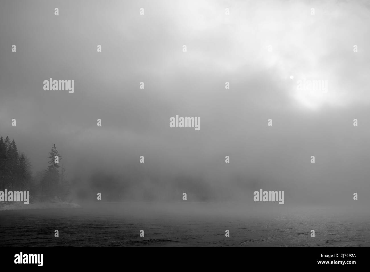 Gloomy fog atmosphere with sun shining through on the shore of Walchensee in winter Stock Photo