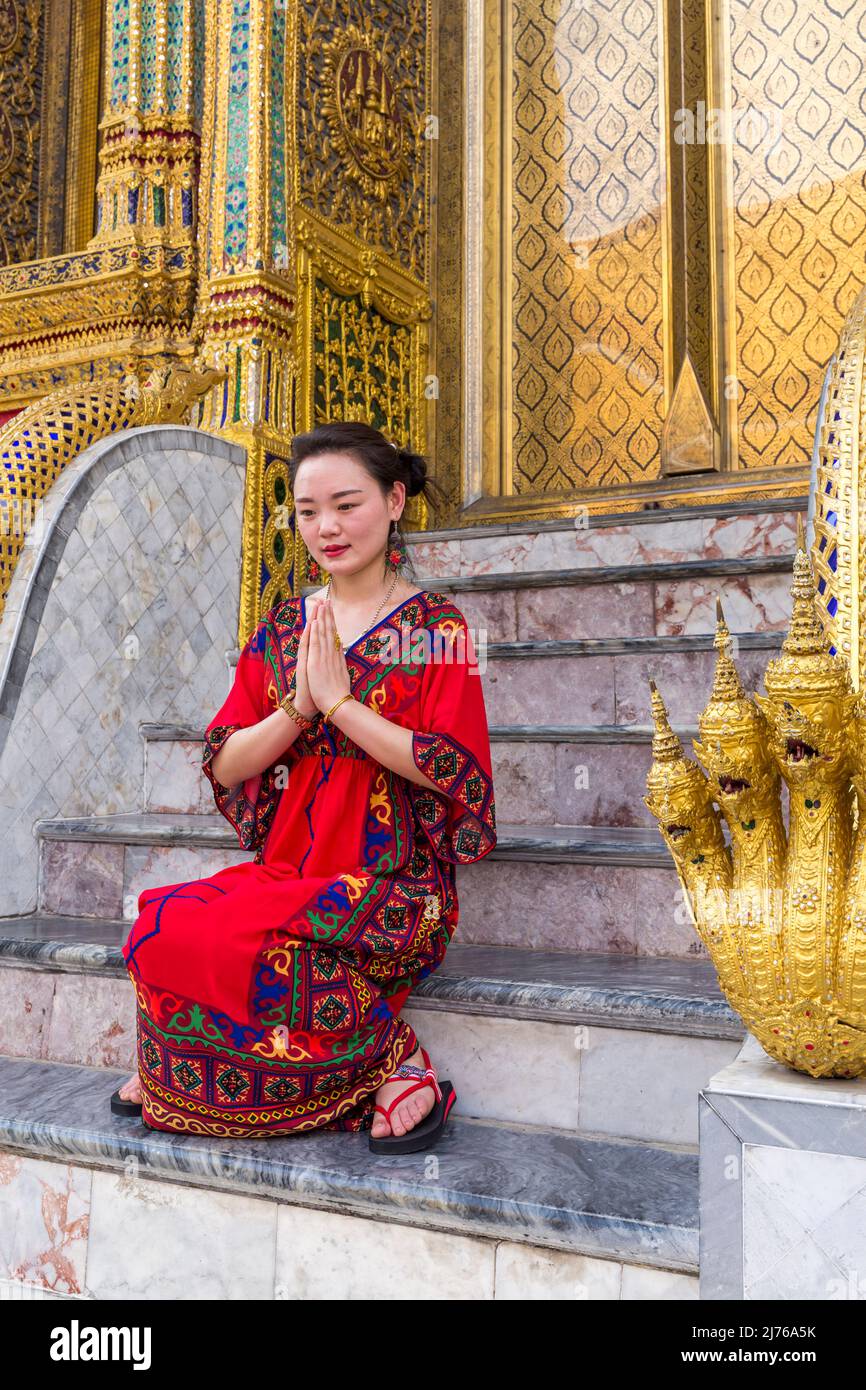 Young woman prays and has her picture taken by tourists, Royal Palace, Grand Palace, Wat Phra Kaeo, Temple of the Emerald Buddha, Bangkok, Thailand, Asia Stock Photo