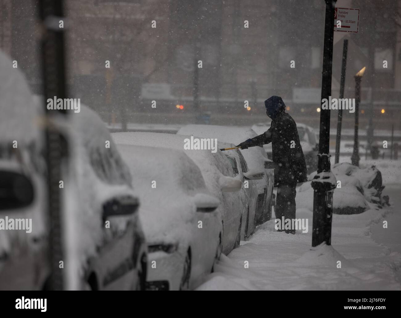 NEW YORK, N.Y. – February 1, 2021: A person removes snow from a vehicle in Battery Park City during a winter storm. Stock Photo
