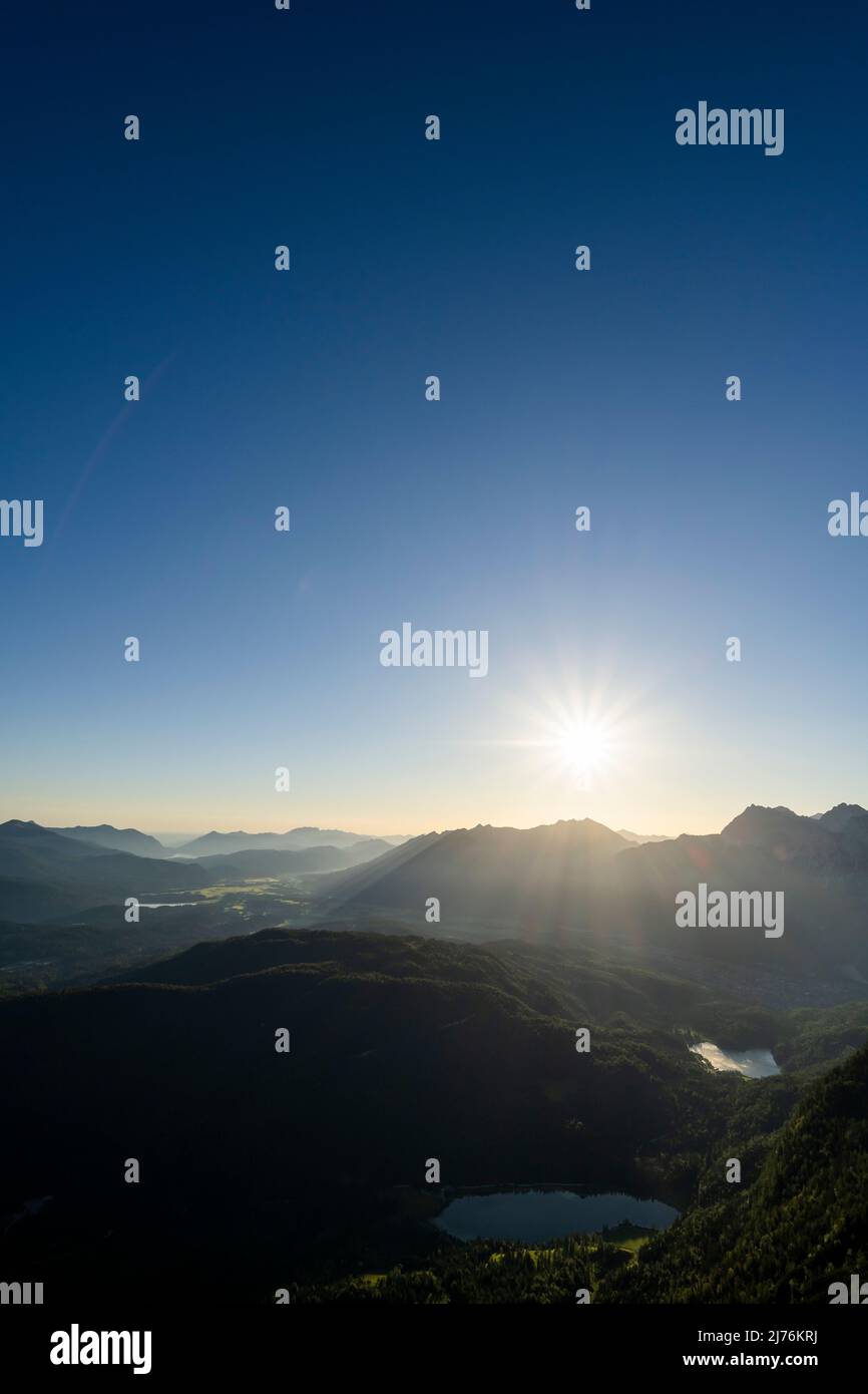 Sun star over Karwendel, Ferchensee and Lautersee, as well as the forested Kranzberg in Werdenfelser Land, on the border with Tyrol/Austria. The two small lakes lie in the dense and dark forest, while in the background the sun rises over the Karwendel. Stock Photo