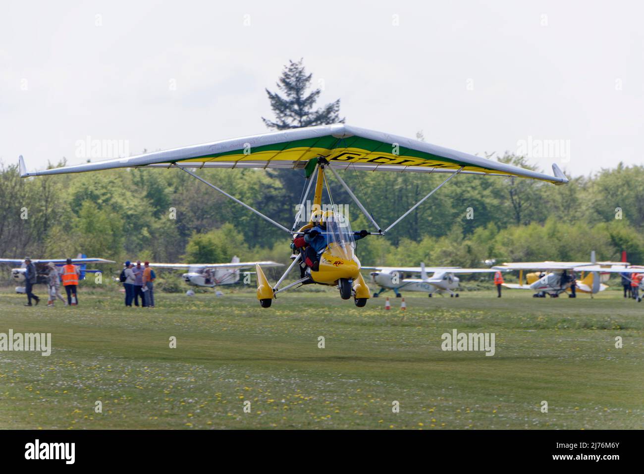 Bright Yellow and Green P and M Aviation Quik GTR weight shift microlight G-CIIH departs Popham airfield in Hampshire England after attending a fly-in Stock Photo