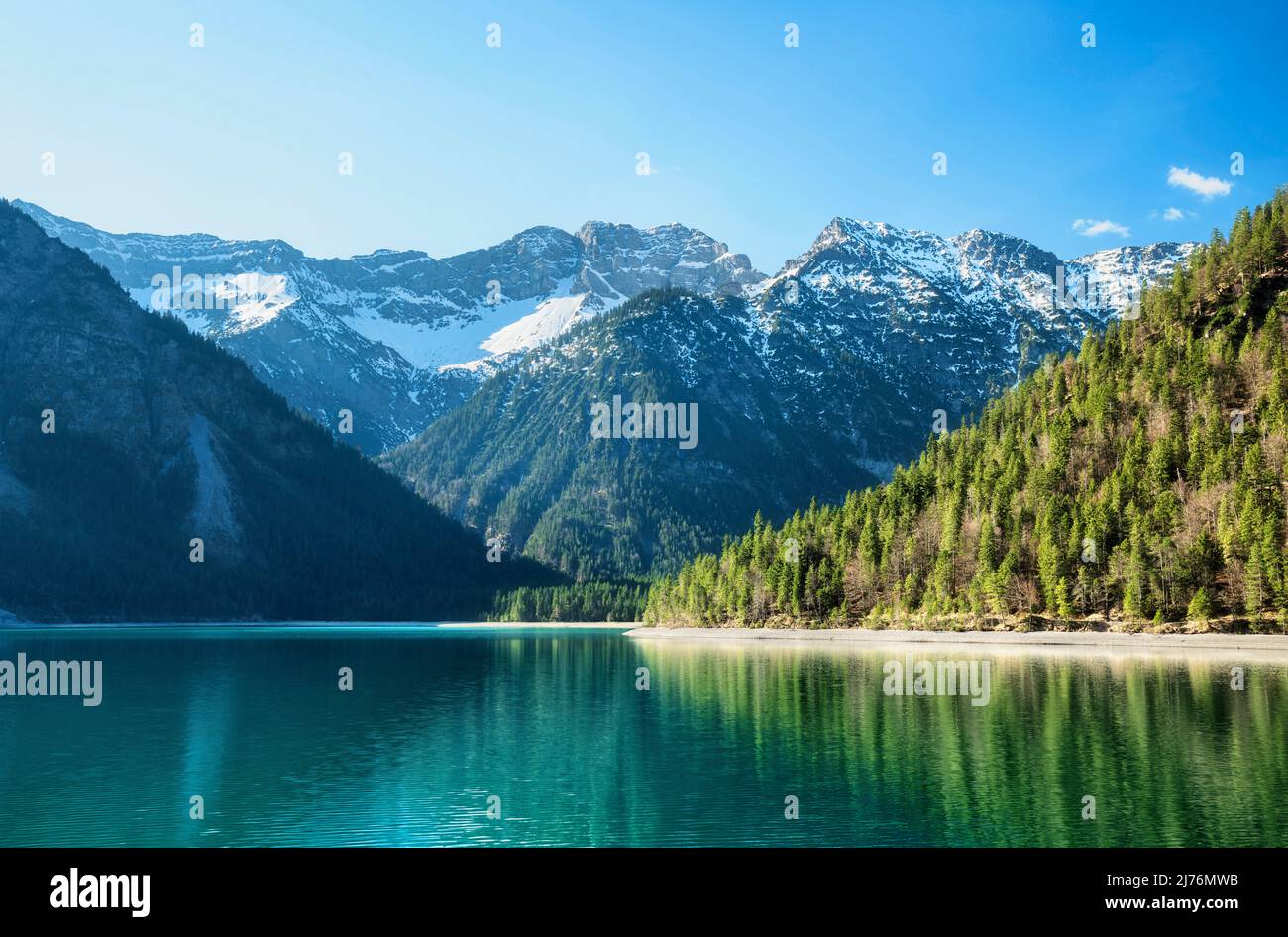Turquoise mountain lake surrounded by green forests and snow-capped ...