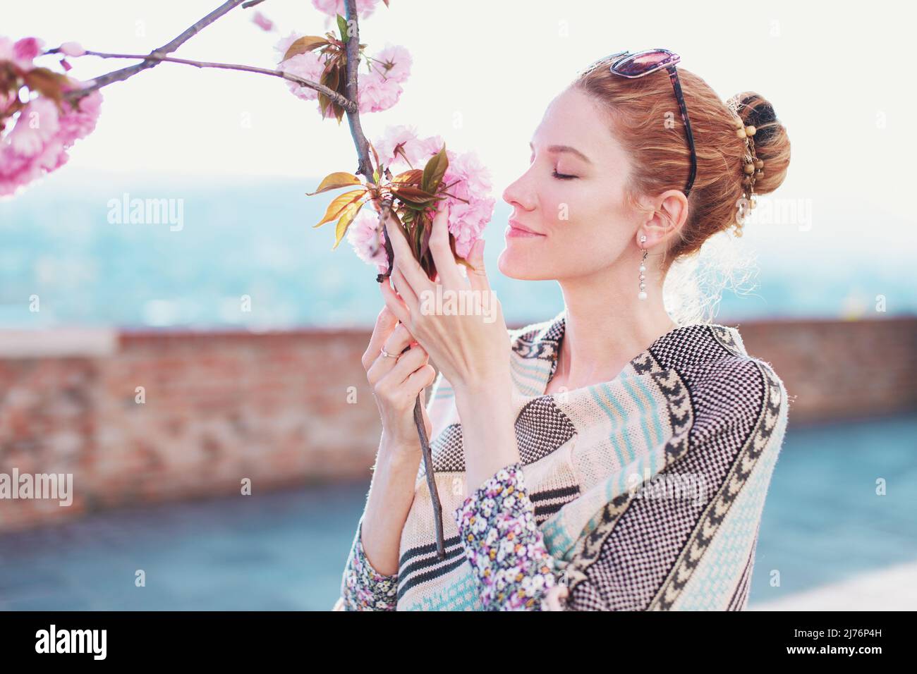 Young redhead Caucasian woman smelling cherry tree blossom Stock Photo