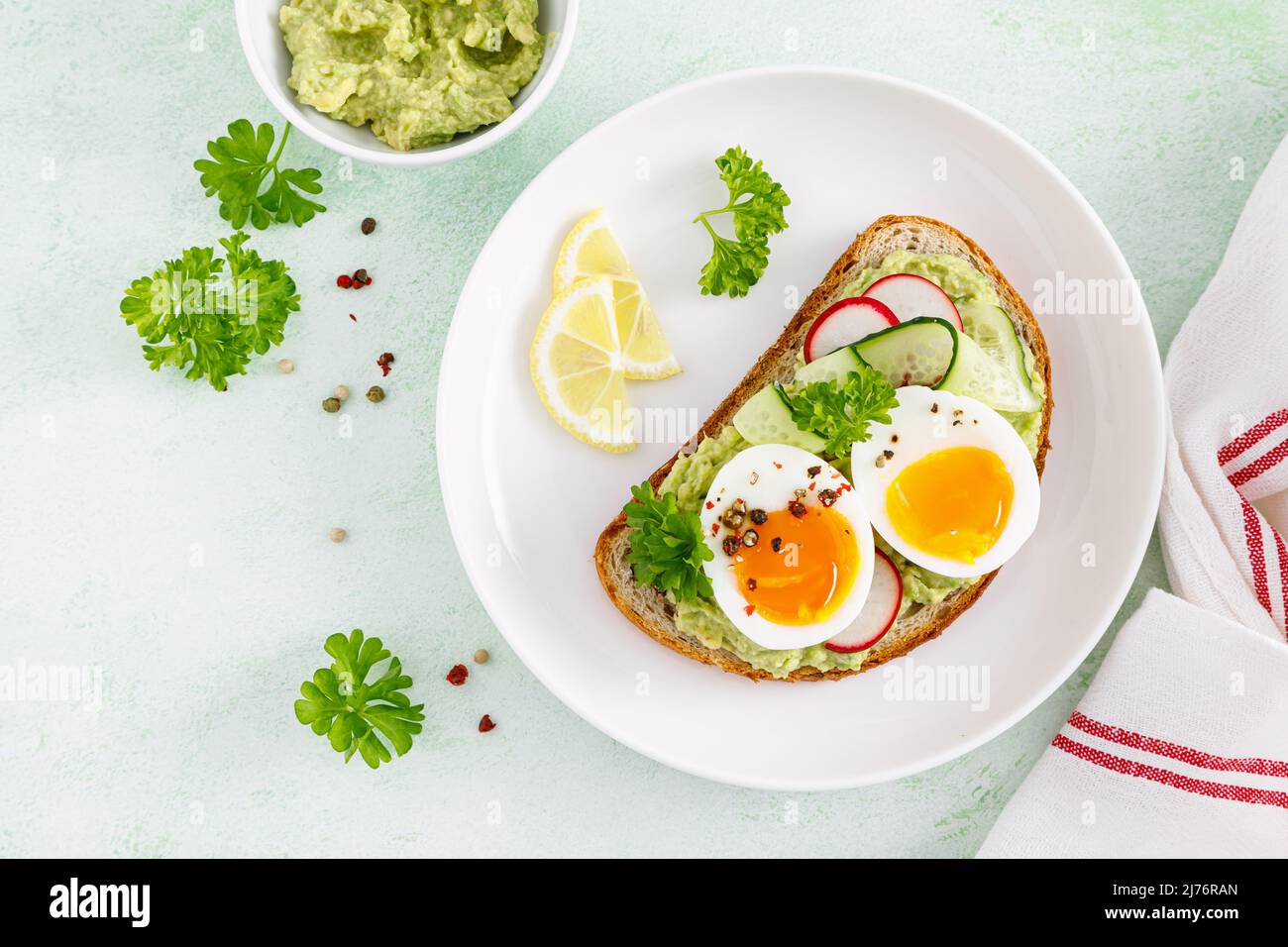 Toast with boiled egg, radish, cucumber and avocado pate. Top view Stock Photo