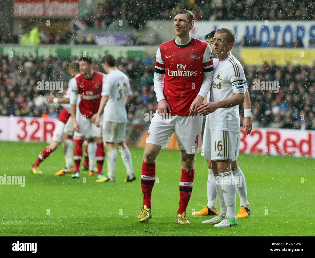 16 March 2013  - Soccer - Barclays Premiership Football - Swansea City Vs. Arsenal -  Per Mertesacker of Arsenal stands with Garry Monk of Swansea City in the rain. - Photo: Paul Roberts / Pathos. Stock Photo