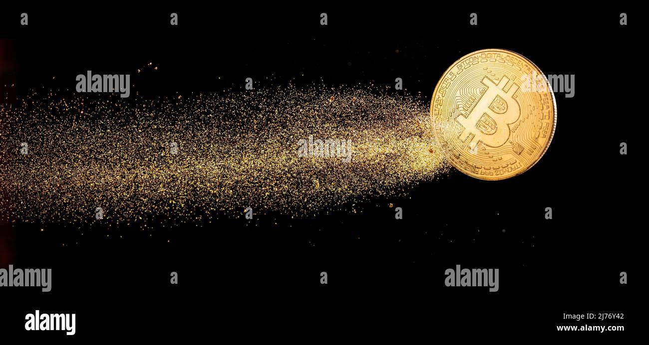 Gold bitcoin with visible gold shining comet tail ath the dark background. Conceptual picture of digital money. Stock Photo