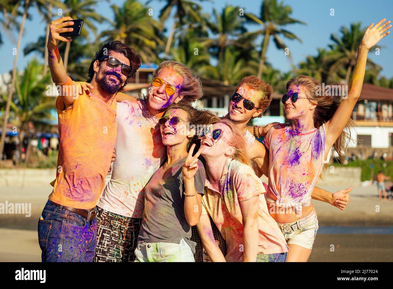 happy people in colorful holi paint play on beach on festive in Goa beach India Stock Photo