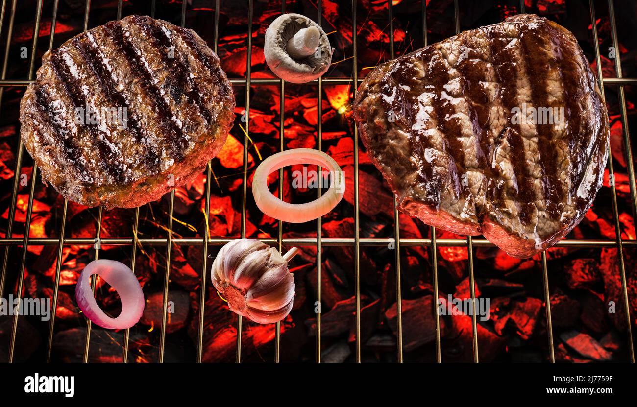 Two grilled beef steaks on bbq grate over hot pieces of coals. Top view