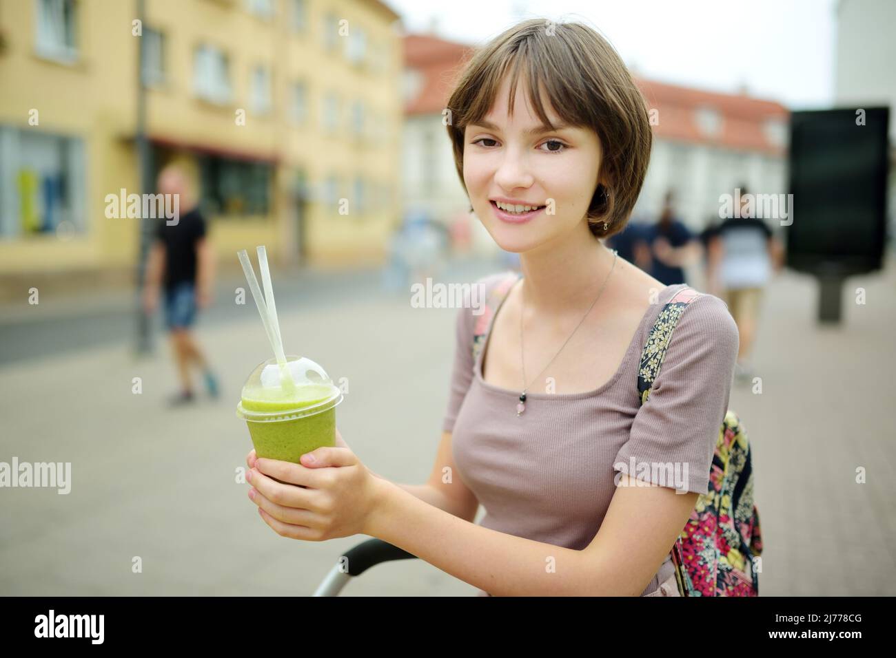 Pretty teenage girl drinking tasty fresh smoothie outdoors on warm