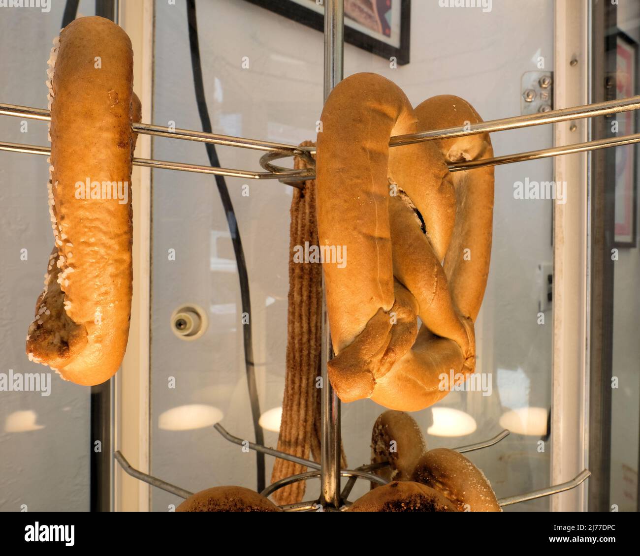 A plain, unsalted pretzel and a salted pretzel in a glass case with a heating element; warm plain pretzels on display for sale to customers. Stock Photo