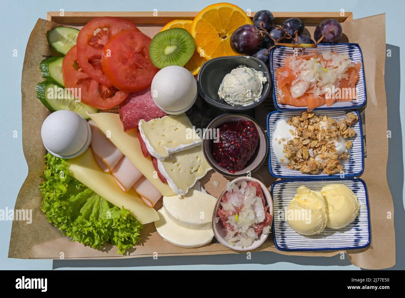 Varied breakfast or lunch for two on a tray with cold cuts, cheese, boiled eggs, fruits and more, high angle top view from above Stock Photo