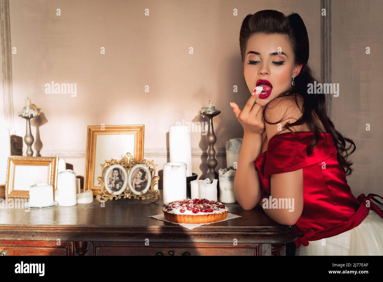 Beautiful pin up model in dress eats berry cake in retro interior Stock ...