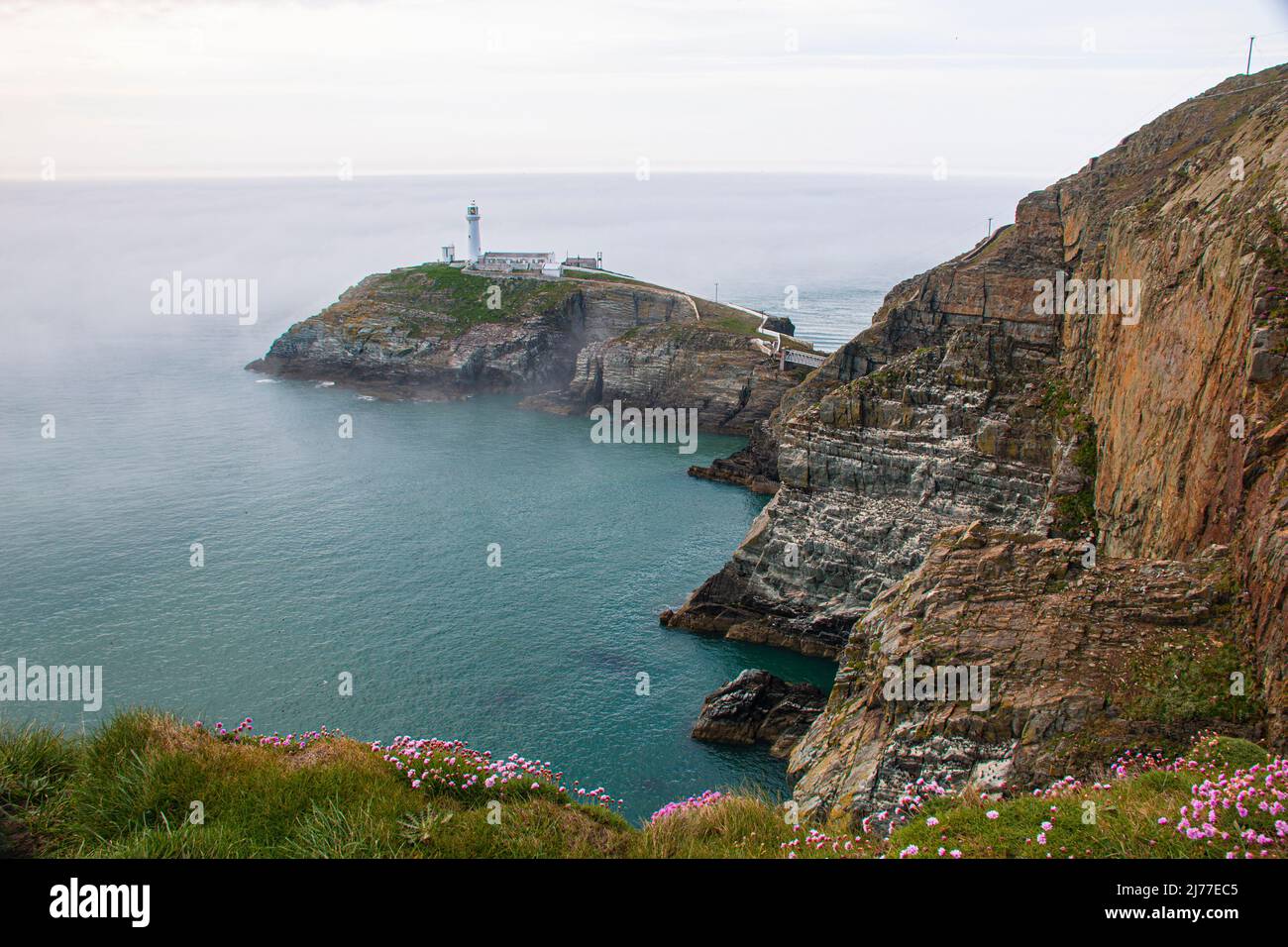 Dramatic cliffs and South Stack Lighthouse, Holyhead, through the morning mist, Angelsey, North Wales Stock Photo