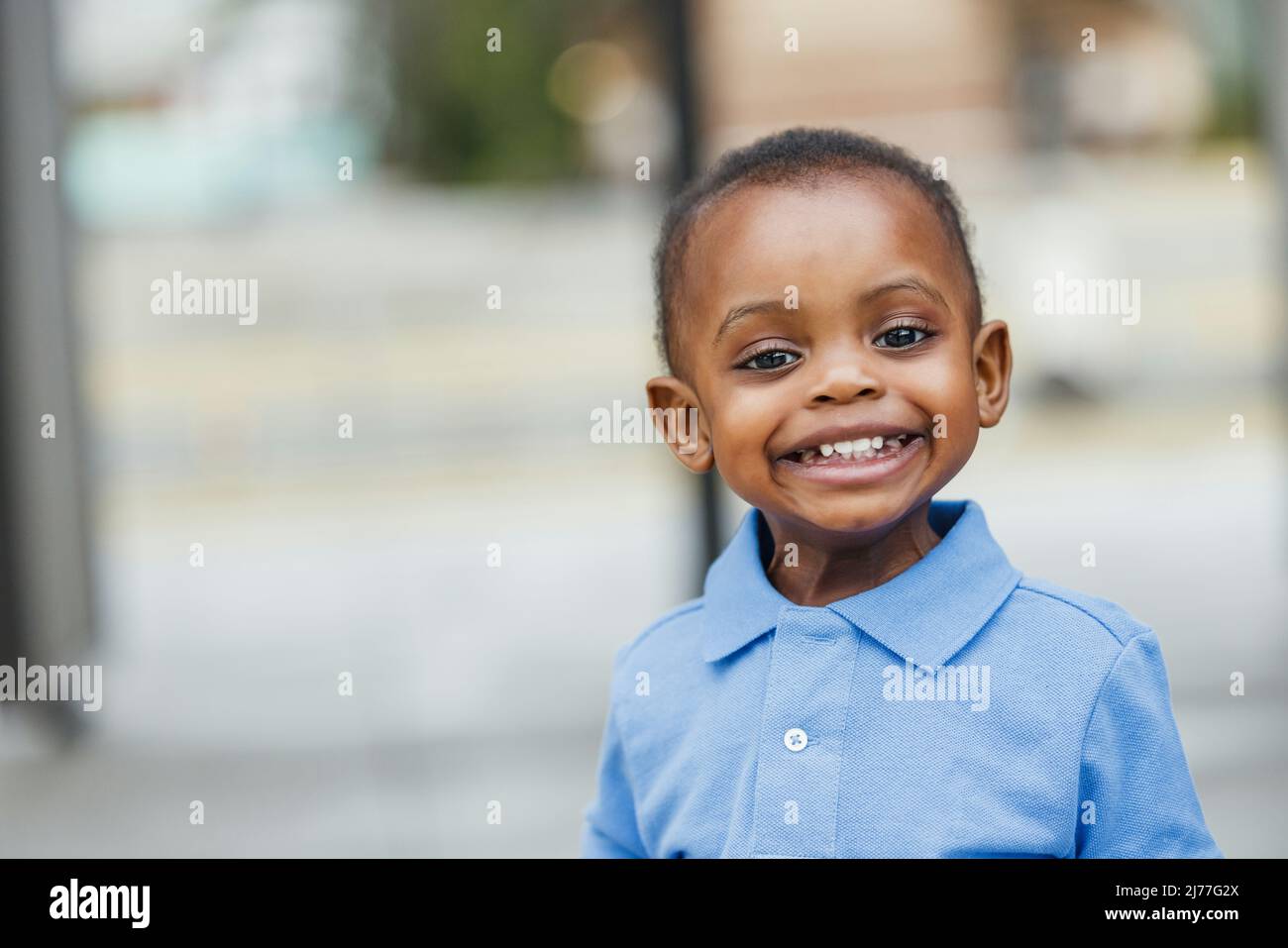 A cute one year old toddler almost preschool age African-American boy with big eyes smiling and looking away with copy space Stock Photo