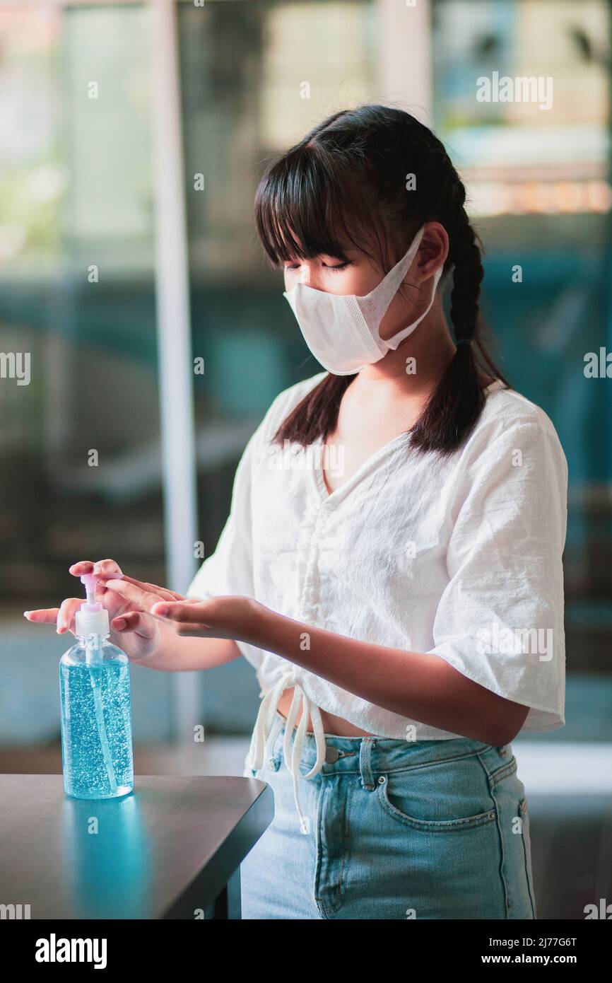 asian teenager wearing protection face mask washing hand by gel alcohol Stock Photo