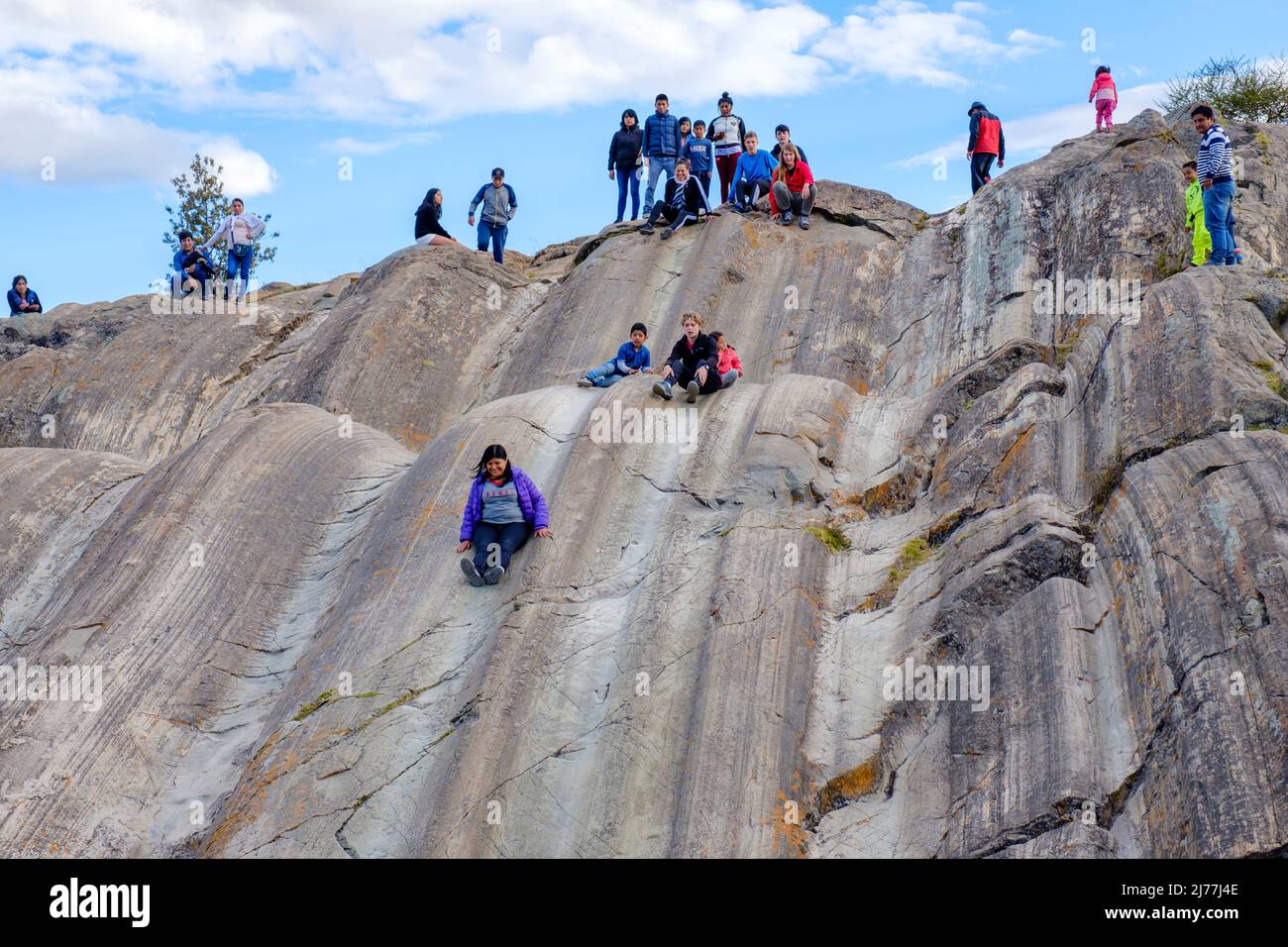 People playing at Sacsayhuaman fortress natural stone formation used as a slide, city of Cusco, Sacred Valley, Peru Stock Photo