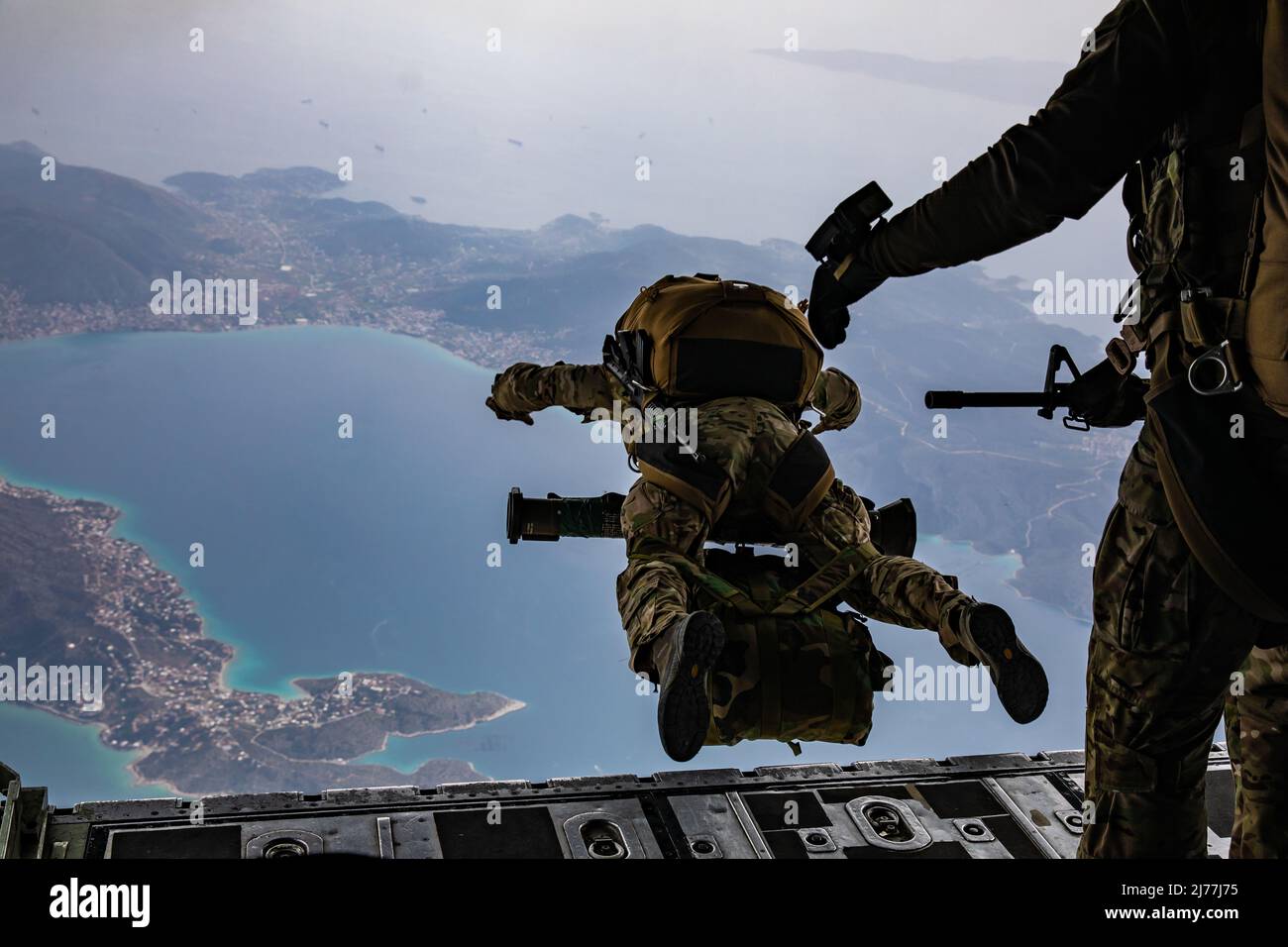 In preparation for Exercise Orion, a U.S. Army Green Beret assigned to 10th Special Forces Group donned in full combat equipment dives from the ramp of a Greek Air Force C-130 aircraft during airborne operation over a coastal area near Elefsina, Greece, March 30, 2022. Exercise Orion reinforces Greece as a regional Special Operations Forces leader, enhances interoperability across multiple domains, and strengthens relationships with NATO and non-NATO partners. The exercise focuses on highlighting operational capabilities, international collaborations and conventional and hybrid warfare trainin Stock Photo