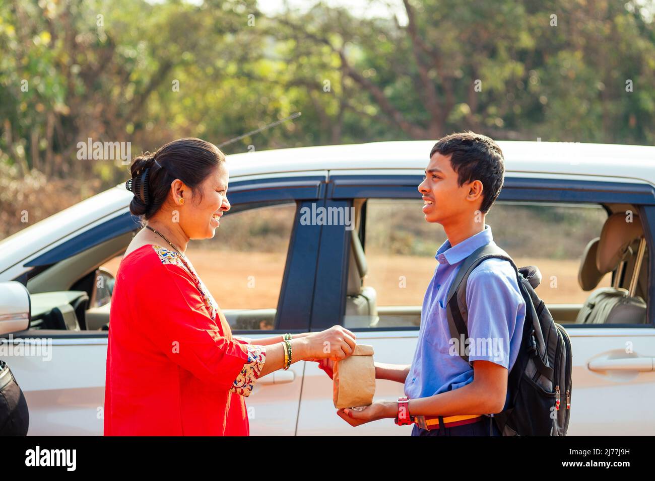 indian family driving boys to school In front of house gates Stock Photo