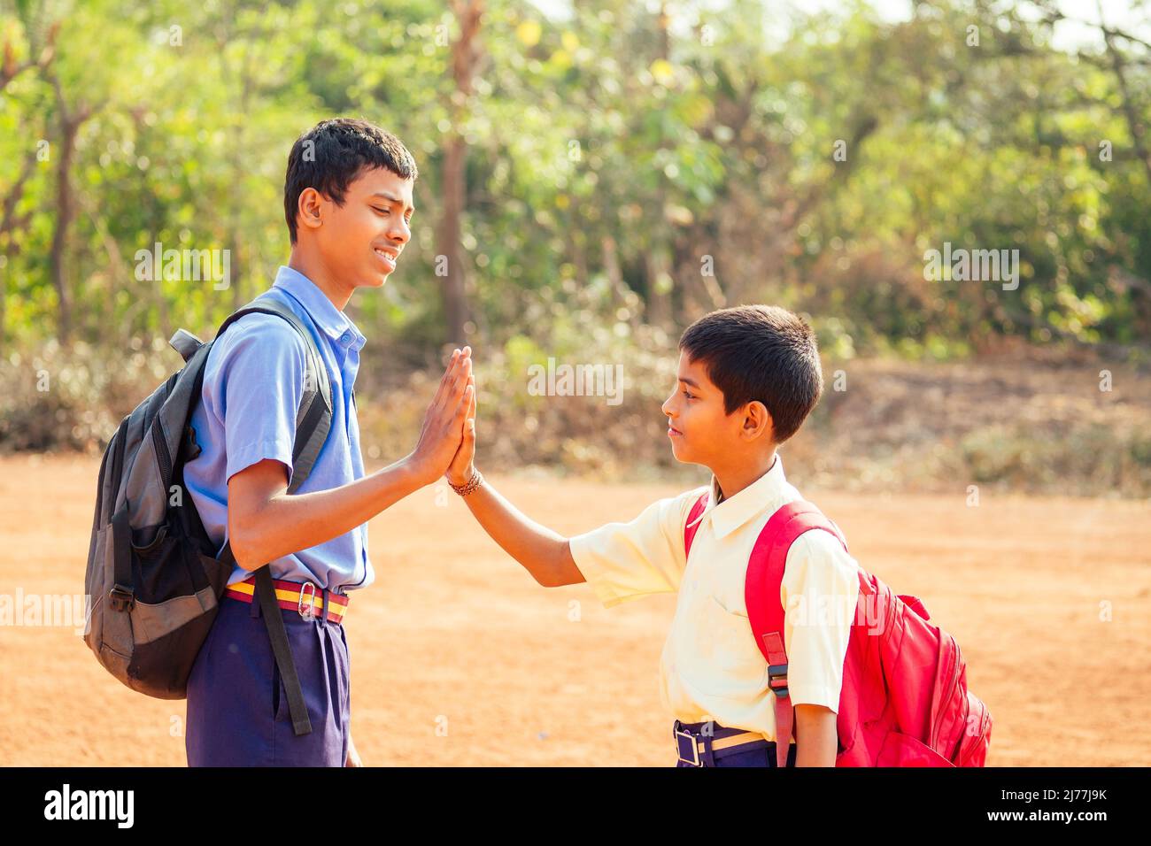 two indian brothers meeting at school and giving high five in Goa outdoors Stock Photo