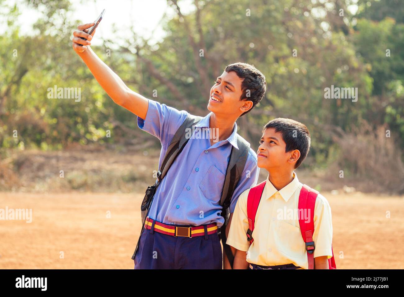 two indian brothers going to school and making selfie photo on smartphone camera in Goa outdoors Stock Photo