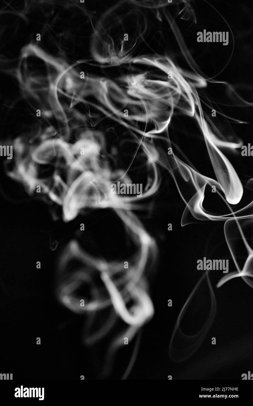 A white, swirling, ascending smoke pattern on a black background, photo could be used as a background, smoke texture or abstract, or general stock pho Stock Photo