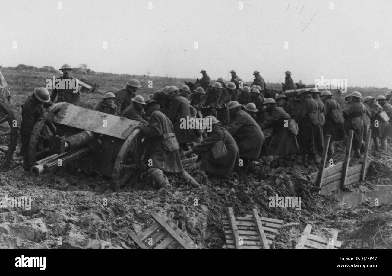 Soldiers trying to extract a field gun from the quagmire. In the foreground there is a pile of duckboards lying unused. Stock Photo