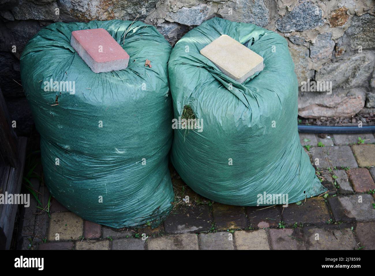 Overhead view of two huge green bags with compost, next to the fence of