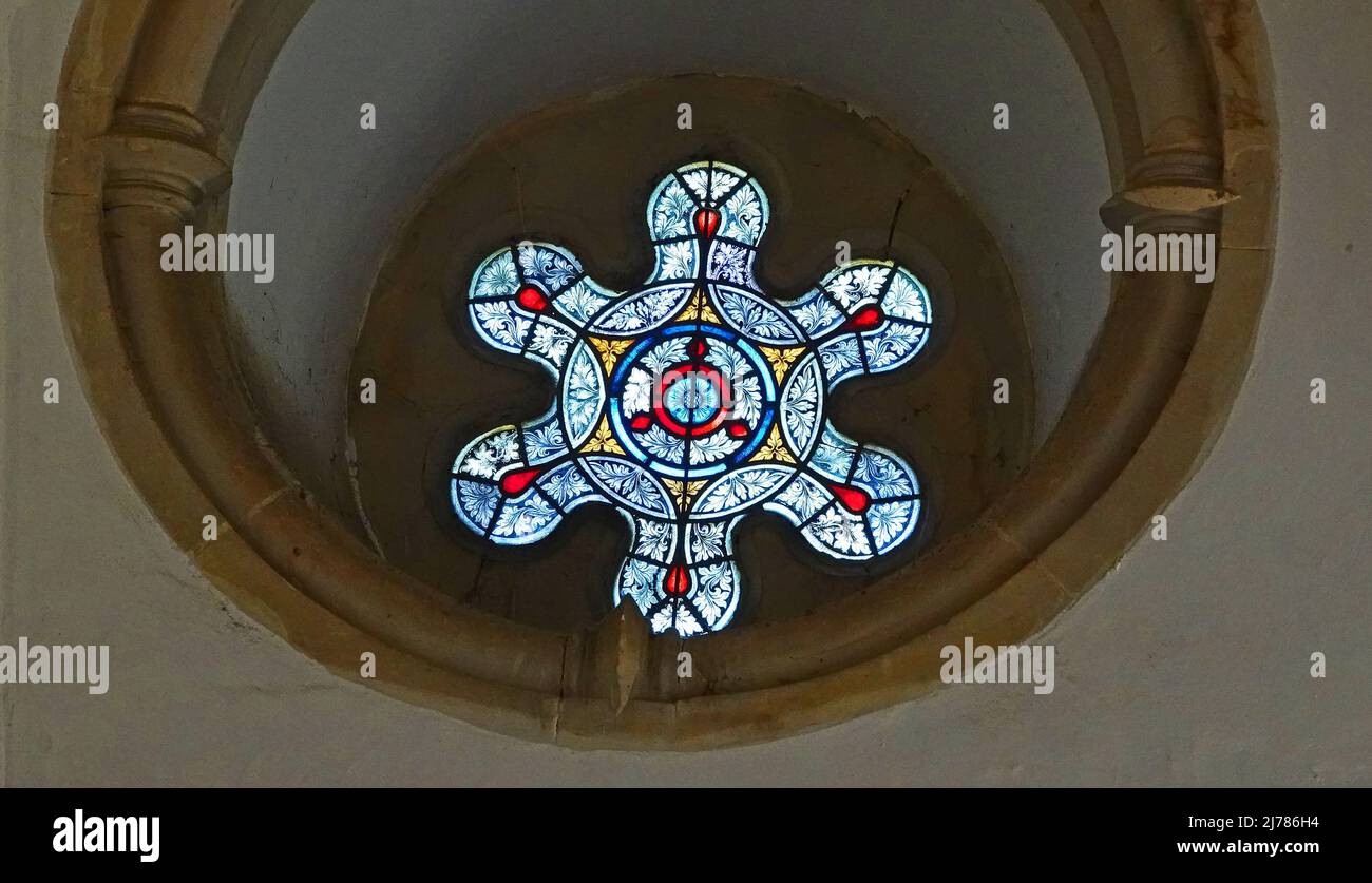A beautiful stained glass window in an old manor. It's a round window ...
