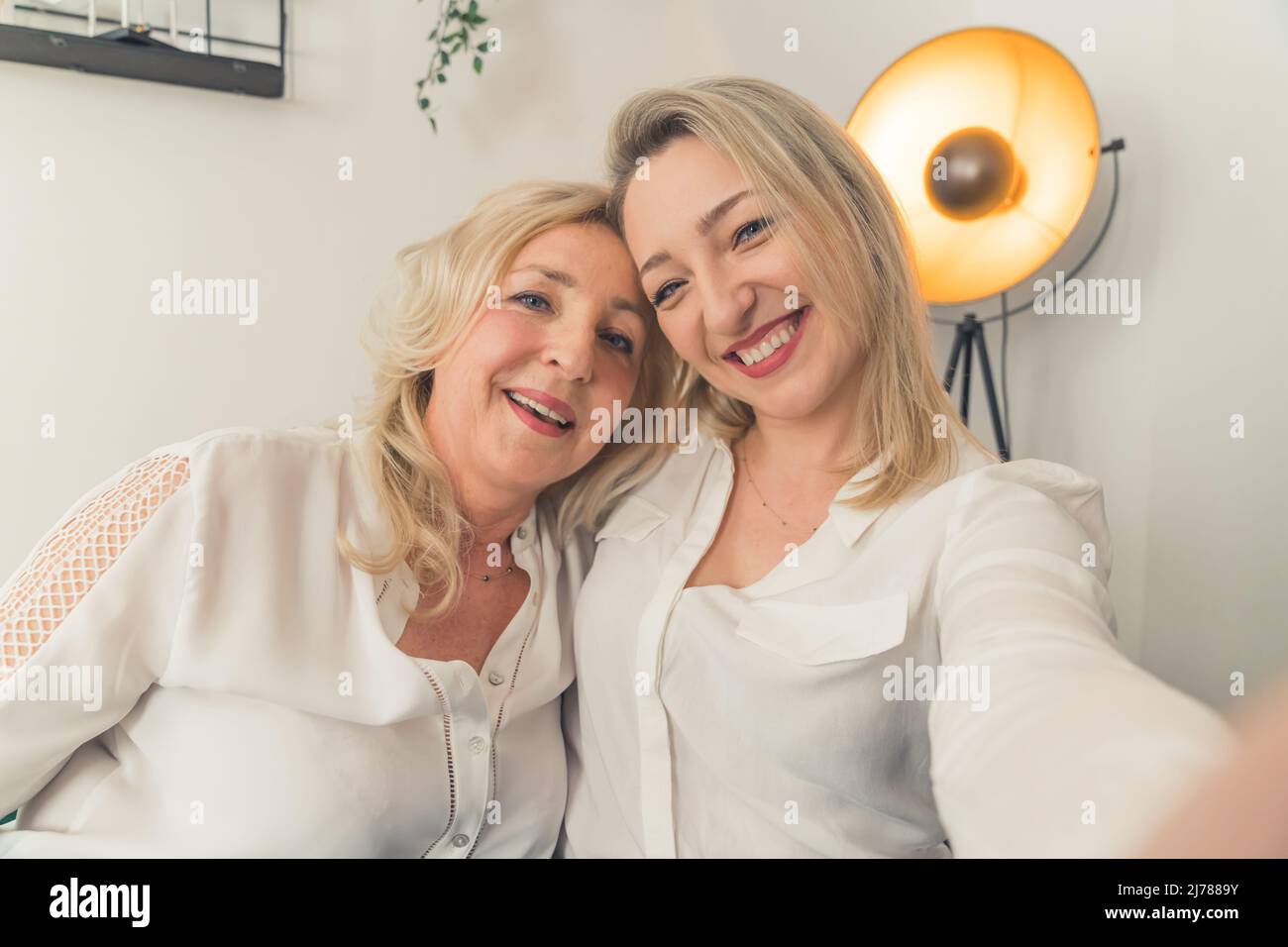 Smiling millennial girl child take selfie with overjoyed funny elderly mother at home, happy grown-up adult daughter have fun make self-portrait picture with mature mom, relax together on weekend. High quality photo Stock Photo