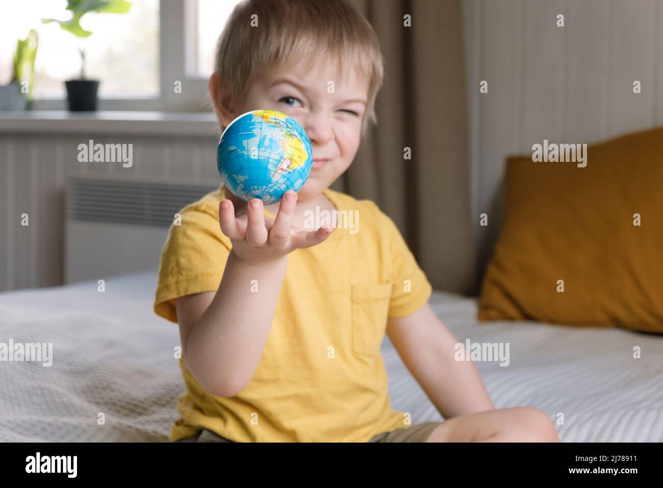 Child boy with blonde hair hugging earth globe, save earth concept. 3 years old kid holding globe model. Baby toddler. Children education development Stock Photo