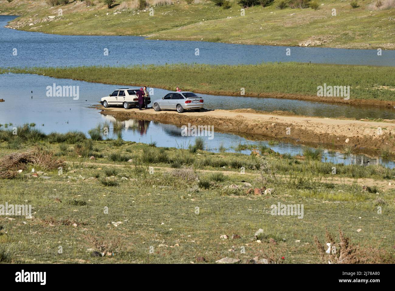 04.05.2022. Manisa. Turkey. People parking very close to lake by old cars. People and car reflection on water. Stock Photo