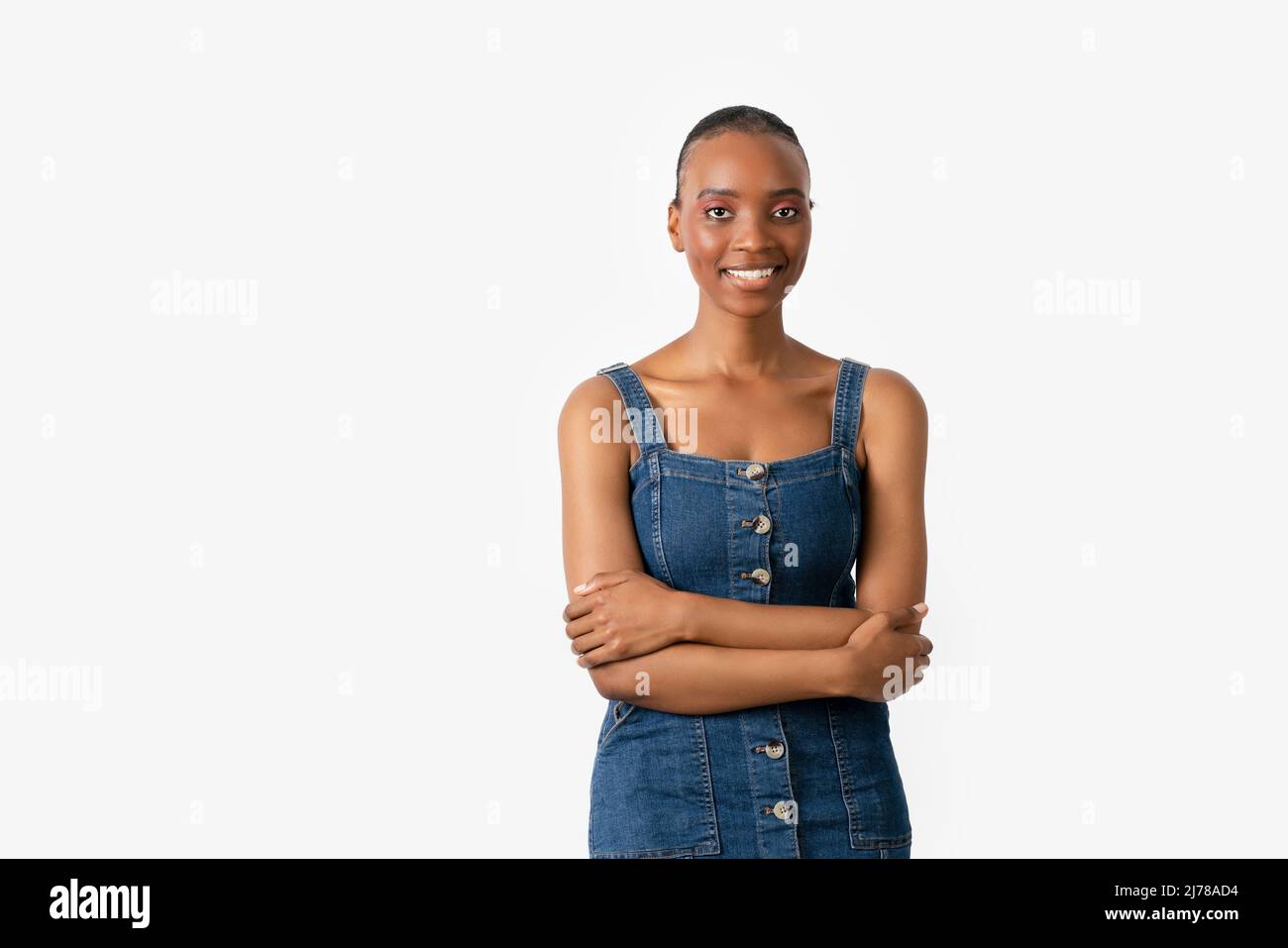 Young and pretty dark skin female isolated on white background crossing her arms and looking to a point with a smily face. High quality photo Stock Photo