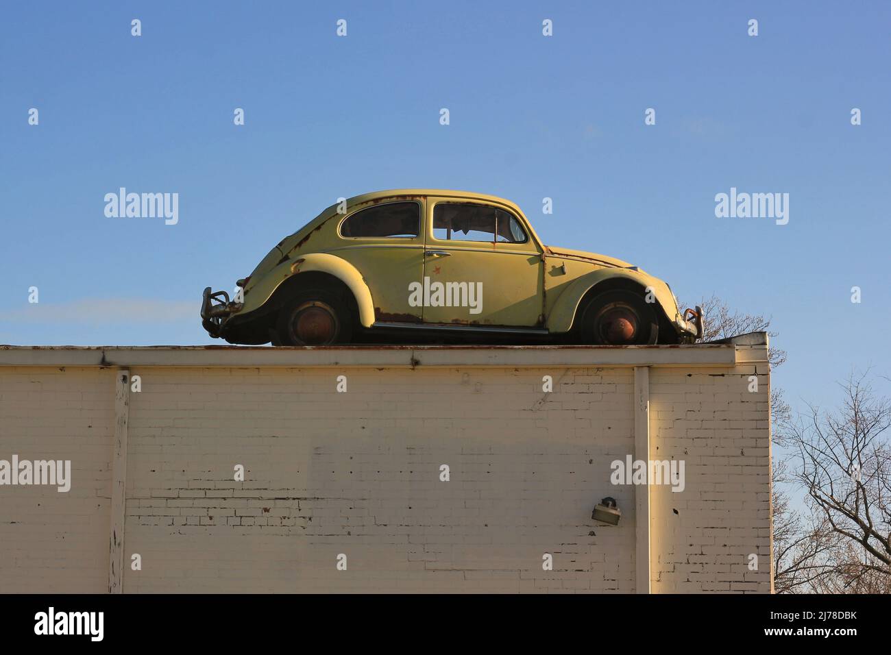 Vintage bright yellow Volkswagen bug beetle stuck on the roof of the
