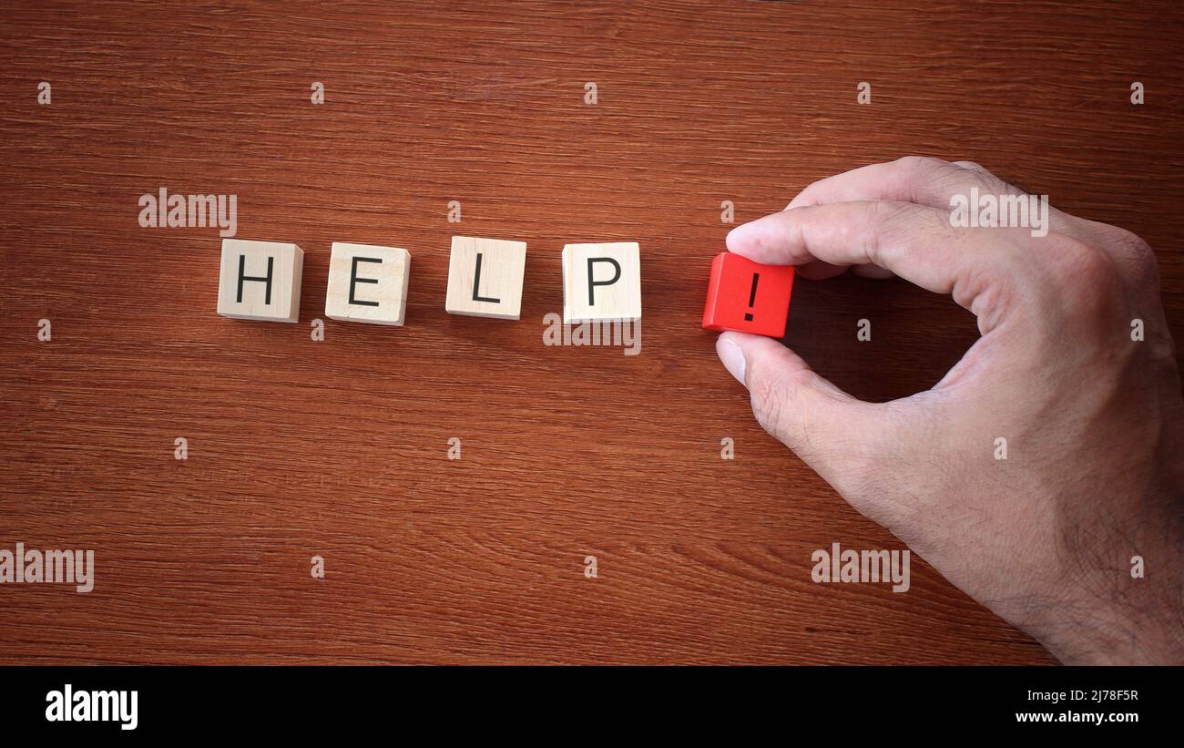 Hand arrange wooden cubes with text HELP on wooden table. Stock Photo
