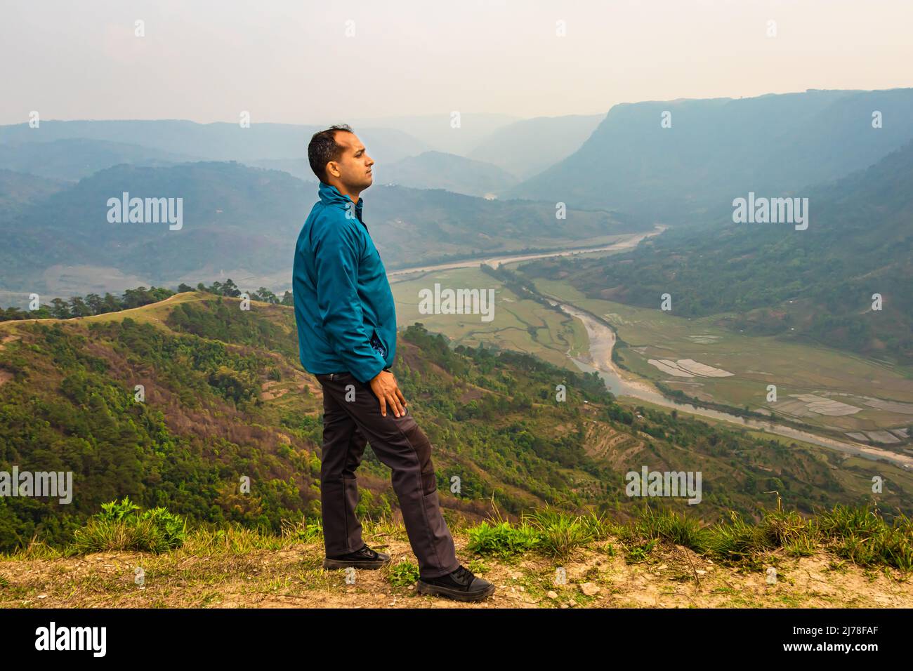 man standing alone at hill top with misty mountain rage background from flat angle image is taken at nongjrong meghalaya india. Stock Photo