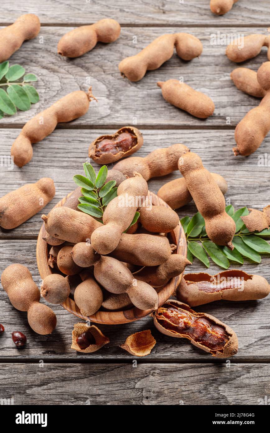Ripe tamarind fruit, leaves and some tamarind seeds on wooden table