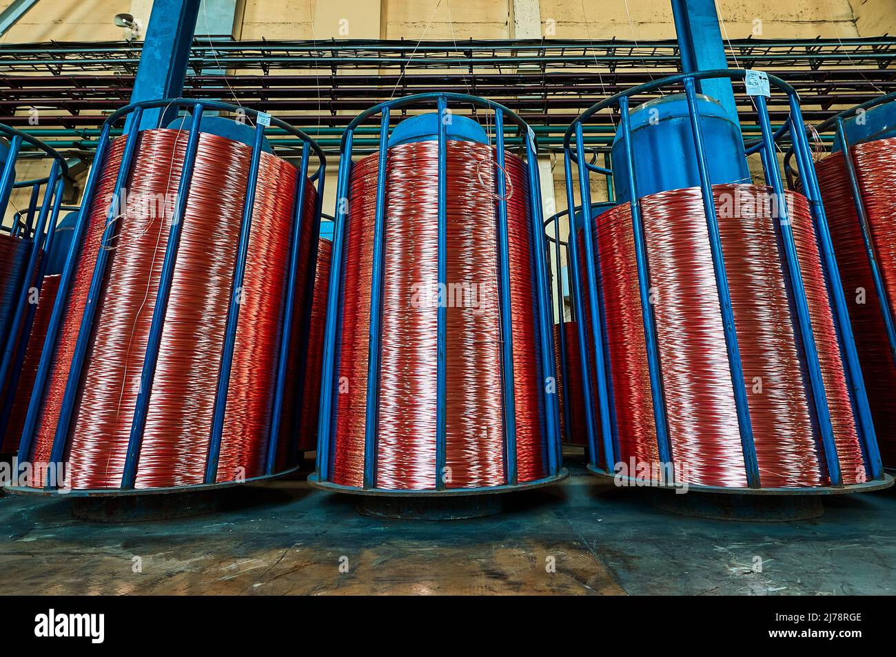 Coiling shiny copper cable onto reels to package at plant Stock Photo