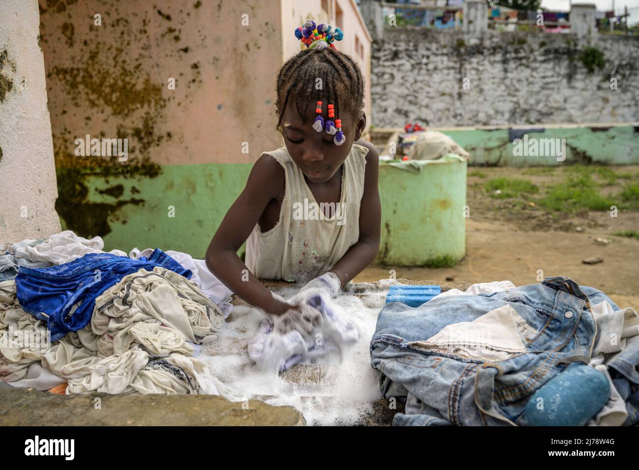 Girl handwashing clothes at the washing place of Roça Agostino Neto. Roça is the name given to the old colonial plantations in Sao Tomé and Principe. Stock Photo