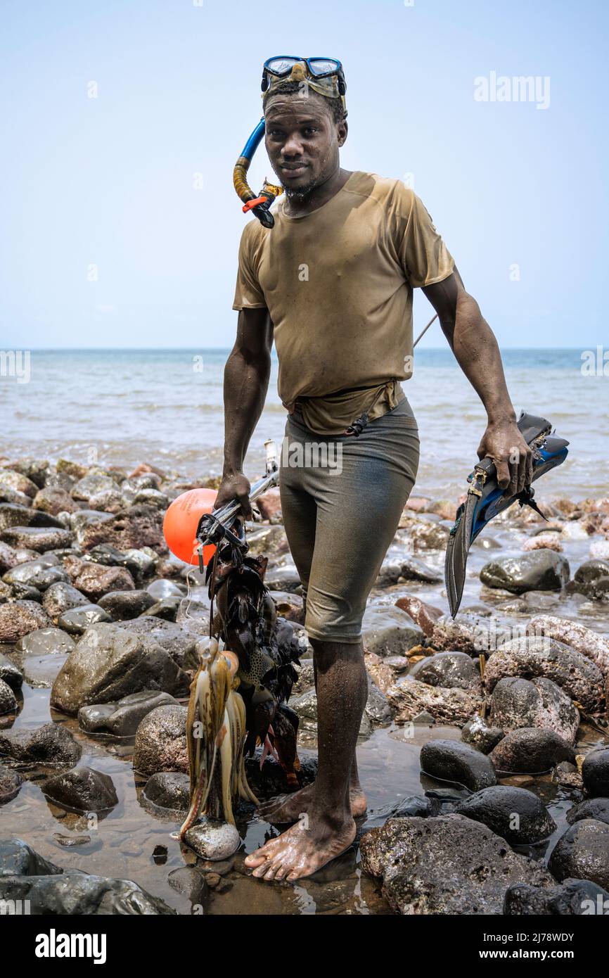 Young fisherman with snorkel gear and harpoon for underwater fishing coming out of the water with the catch of the day. Stock Photo