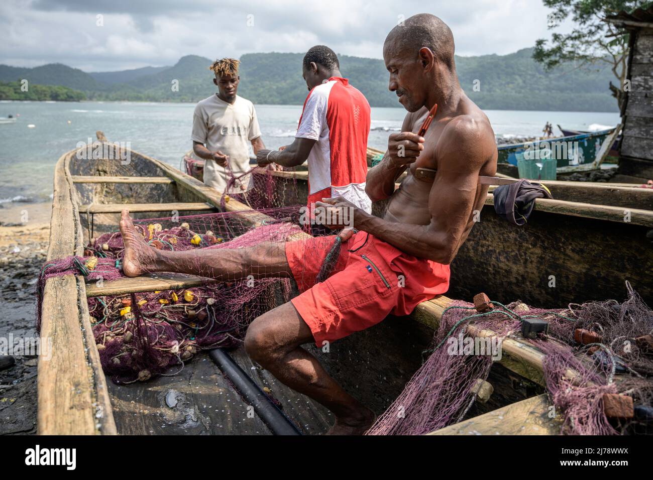 Fishermen repairing the fishing nets on the canoe before going out to fish. Stock Photo