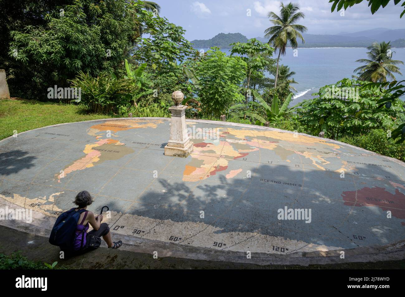 Woman sitting in front of the monument that marks the equator on the island of Las Rolas. Stock Photo