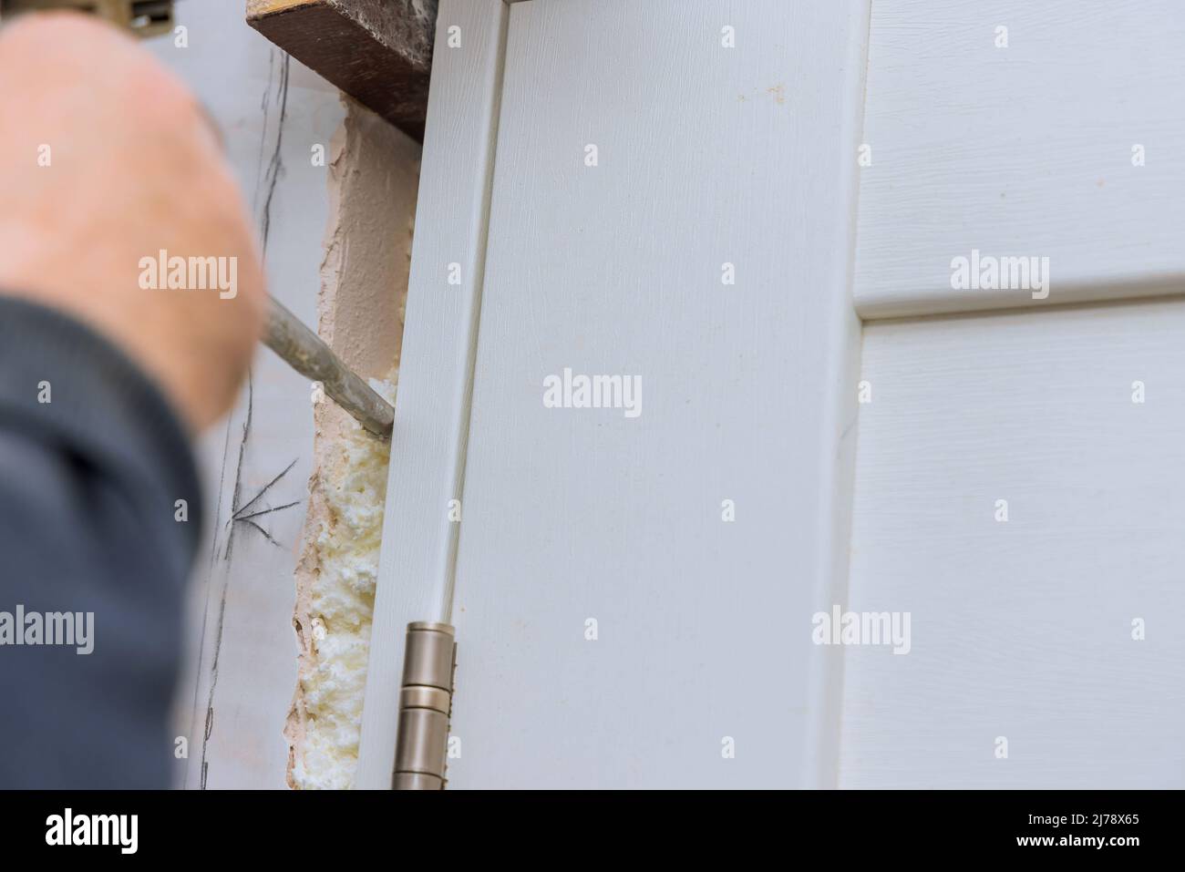 Worker install door, using polyurethane foam to mounting it between at wall Stock Photo