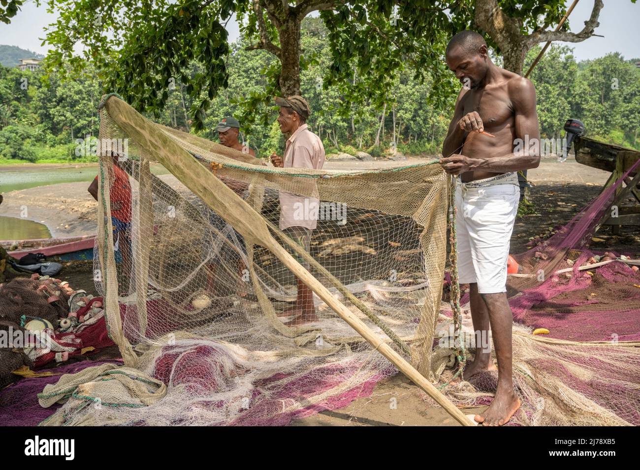 Fishermen repairing the fishing nets before going out to fish. Stock Photo