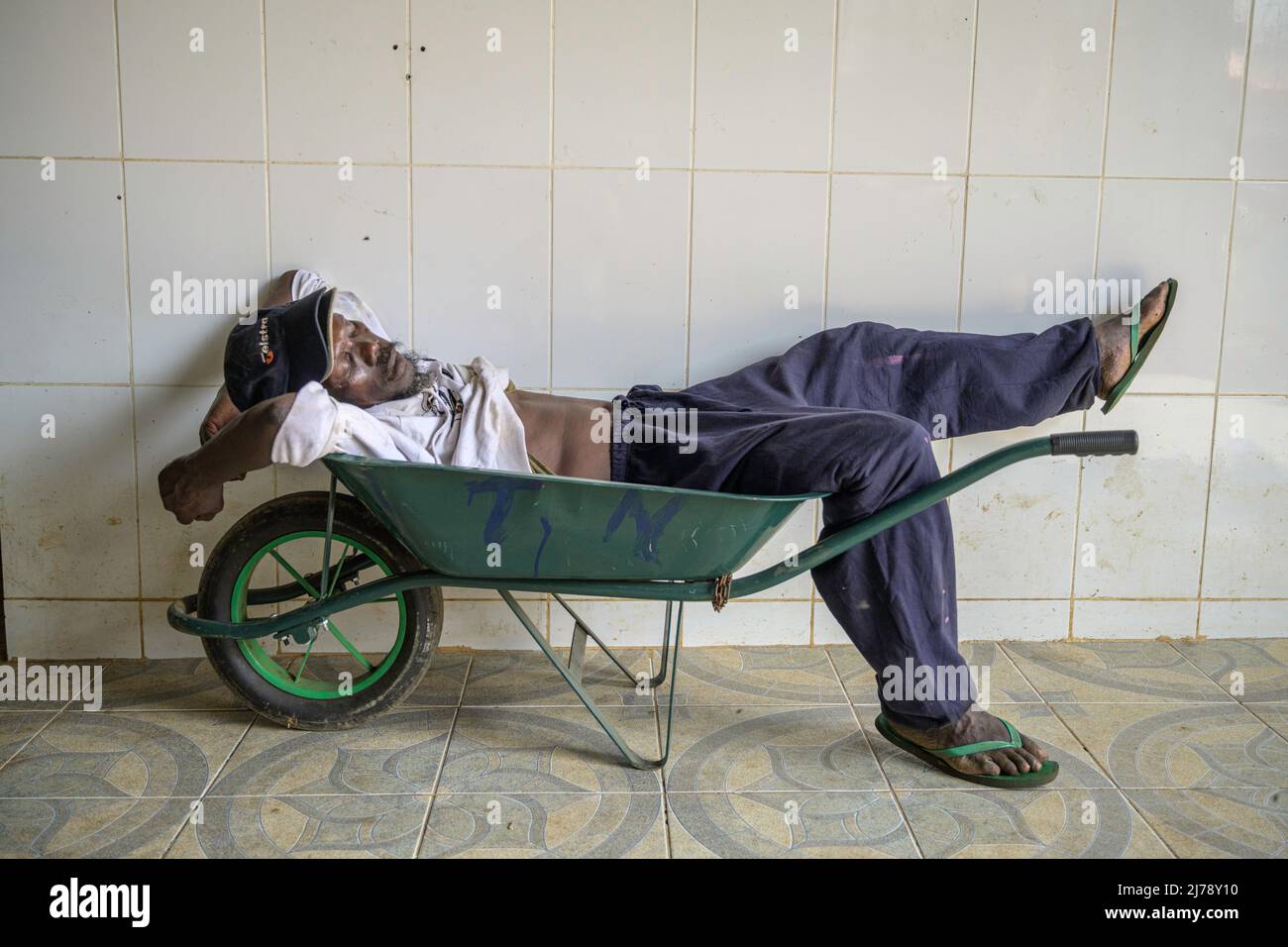 A porter sleeping soundly on a wheelbarrow in the Bobo Forro market. Stock Photo