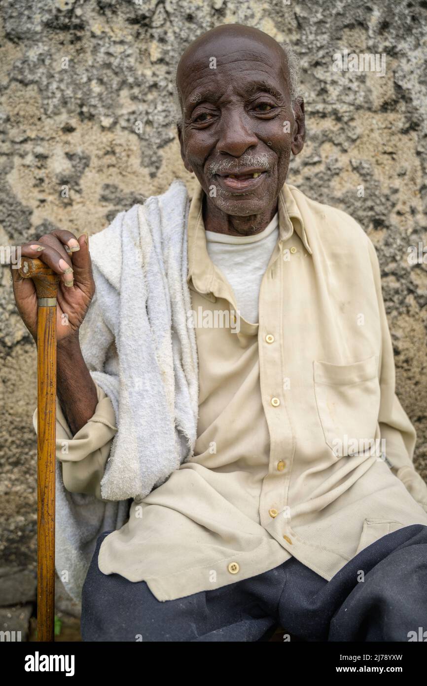 Portrait of seated African old man with walking stick. Stock Photo