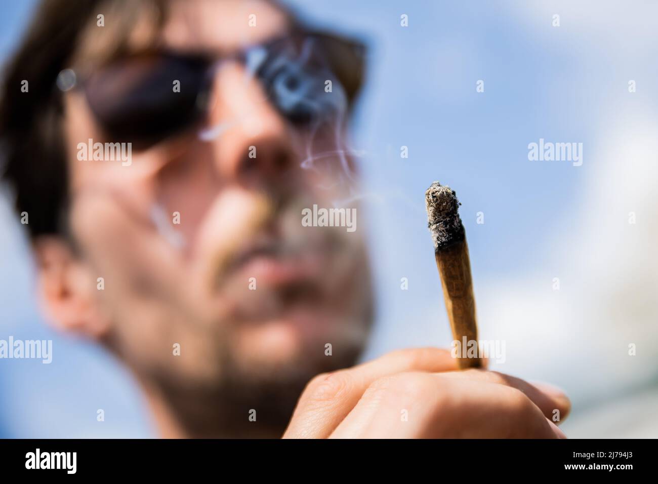 07 May 2022, Berlin: A man smokes a joint of medical cannabis at the Brandenburg Gate during the kick-off rally of a demonstration for the swift legalization of cannabis, the Global Marijuana March 2022. Photo: Christoph Soeder/dpa Stock Photo