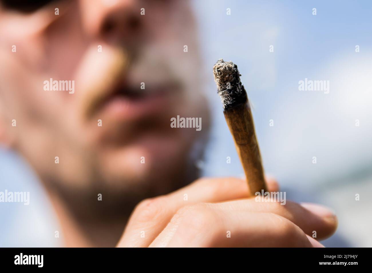 07 May 2022, Berlin: A man smokes a joint of medical cannabis at the Brandenburg Gate during the kick-off rally of a demonstration for the swift legalization of cannabis, the Global Marijuana March 2022. Photo: Christoph Soeder/dpa Stock Photo